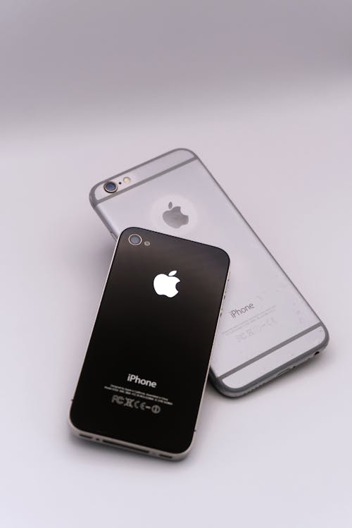 Gratis Dos teléfonos inteligentes sobre una superficie blanca, mostrando un diseño elegante y tecnología avanzada. Foto de stock