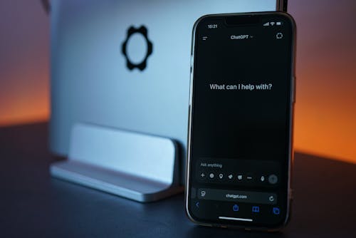 Gratis Primer plano de un teléfono inteligente que muestra una interfaz de chat con una computadora portátil en el fondo. Foto de stock